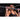Woman pulls herself up on a gym bar, focused effort in a dimly lit fitness studio.